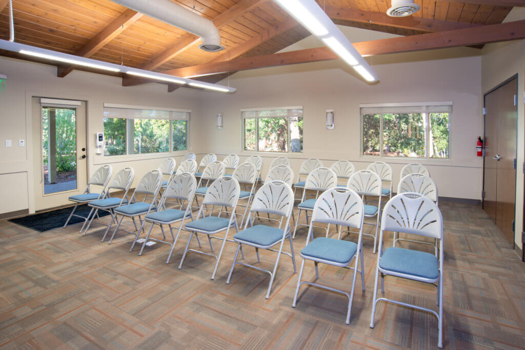 Three rows of white folding chairs, sitting in three rows on a carpeted floor