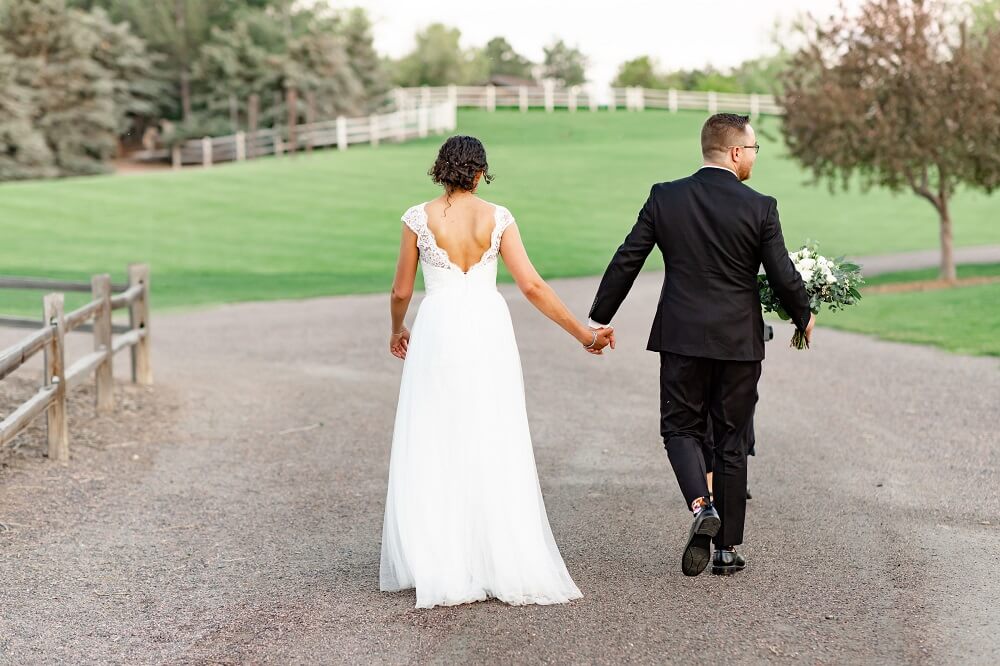 A couple in traditional wedding attire walking away from the camera holding hands