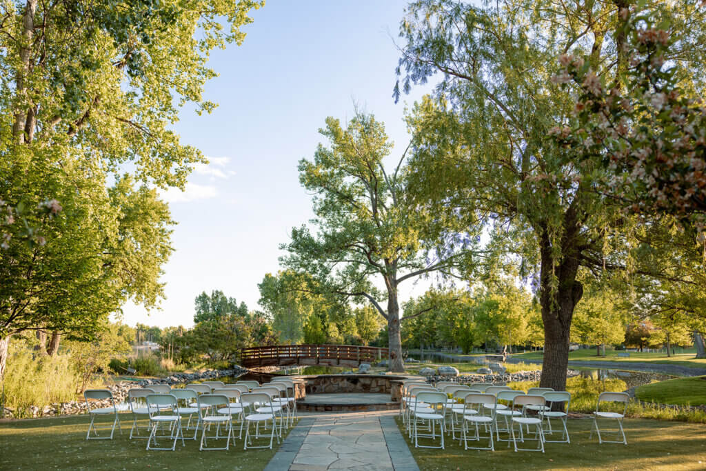 Wedding Ceremony site overlooking water feature with bridge. Rows of white chairs set up in front of site.