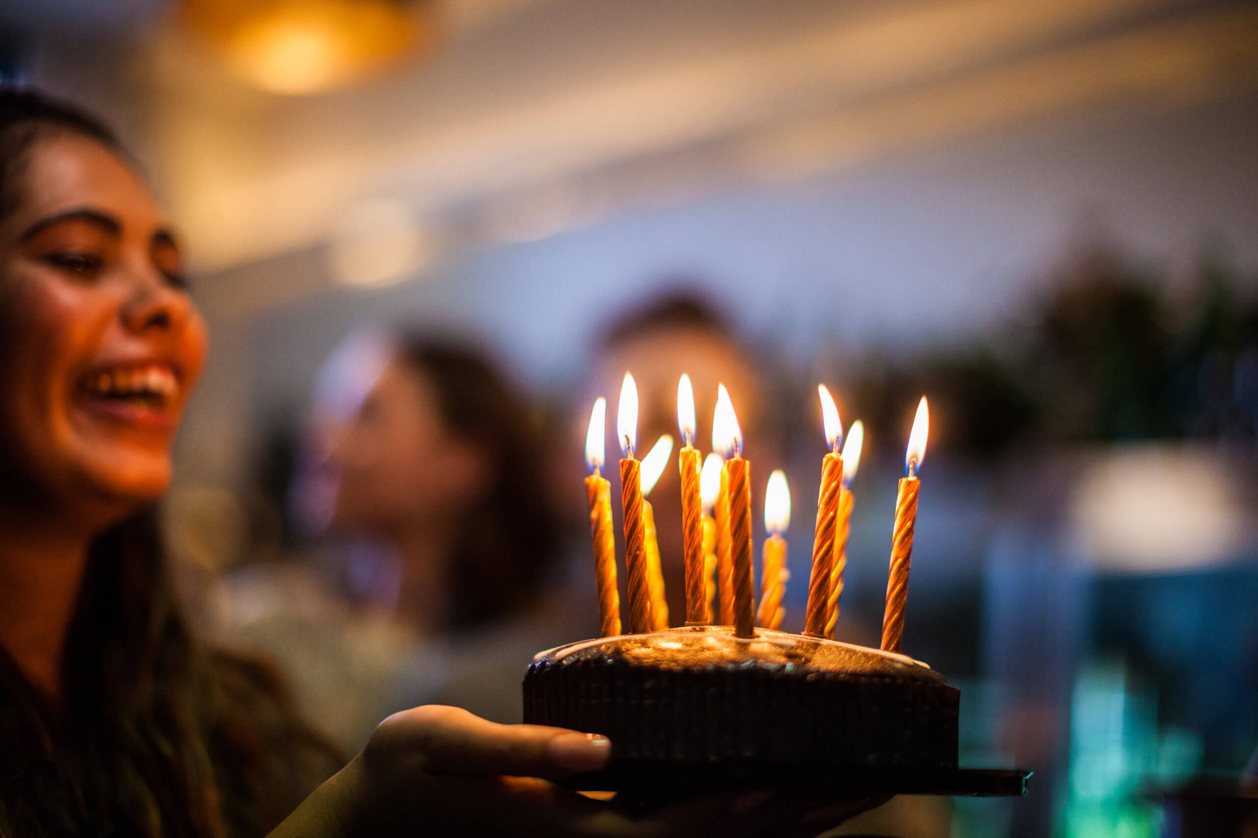 Woman holding cake with lit candles