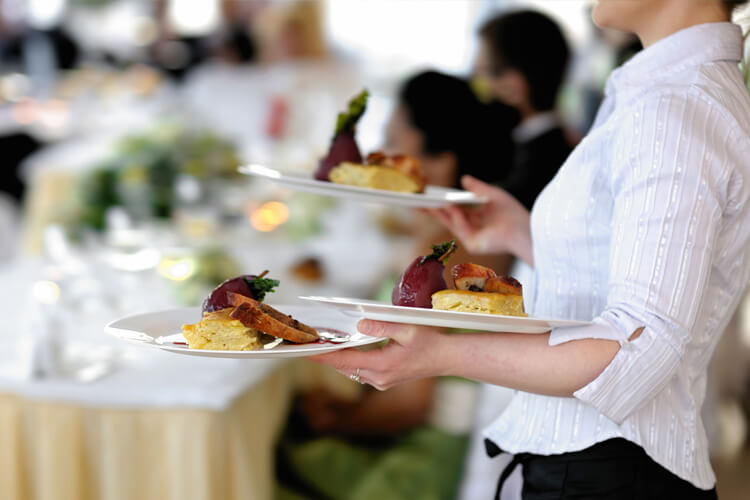 Server holding plates of food at an event