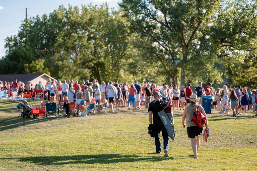 People walking across lawn with camp chairs