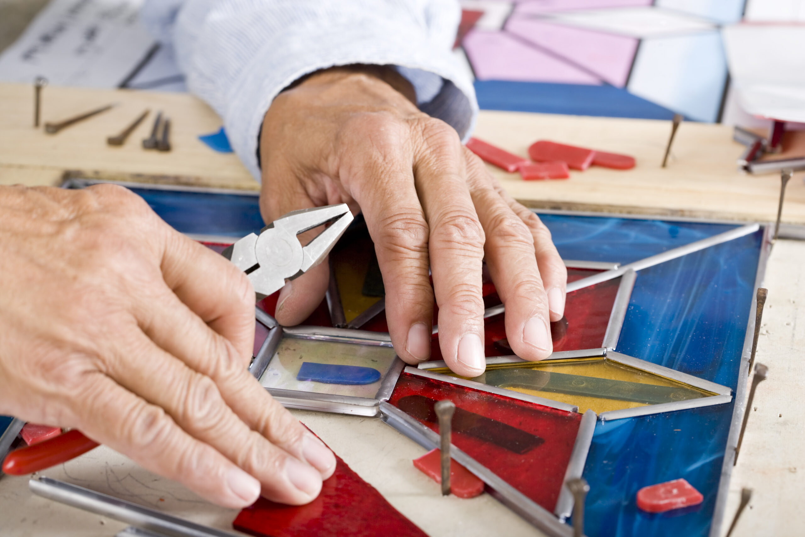 Craftsperson working on stained glass pattern in workshop