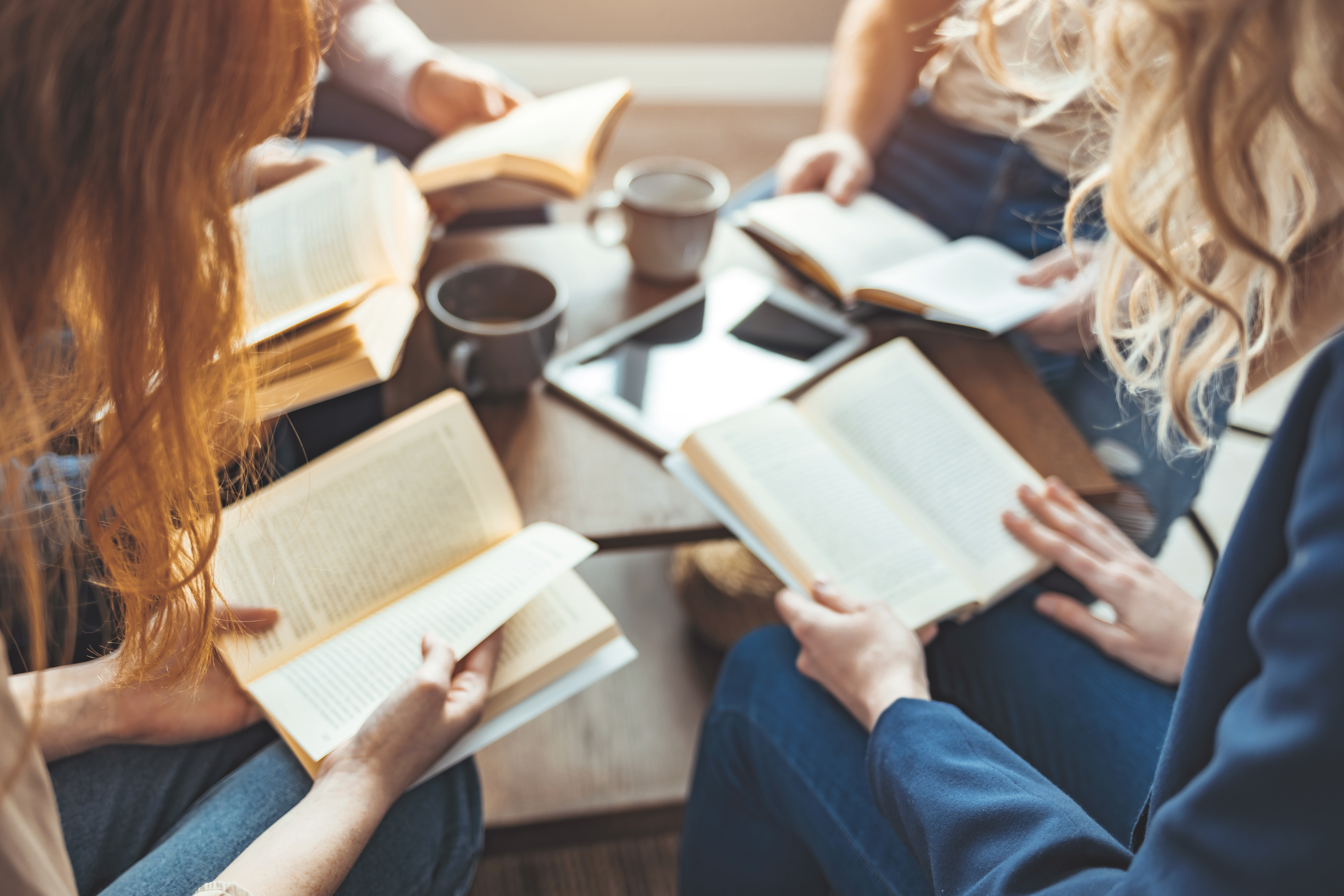 Diverse group of friends discussing a book in library.